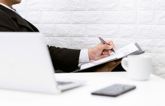 business man working on documents looking computer coffee and phone on the table