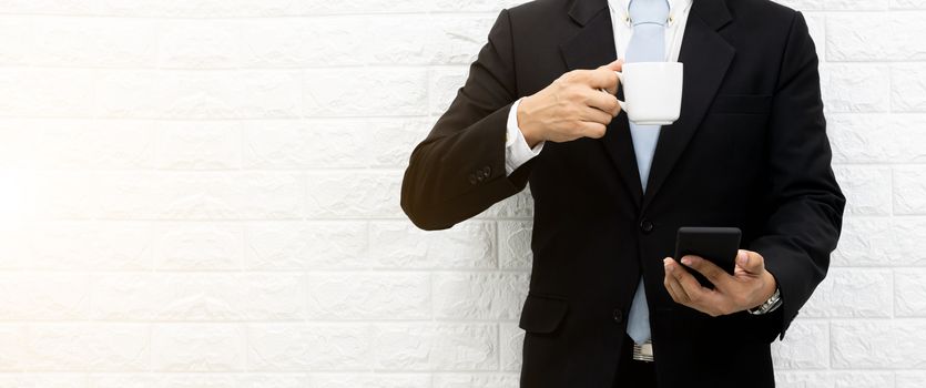 Coffee break businessman Hold a smartphone executive working relax on laptop at his desk.