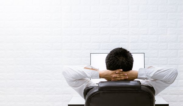 A man happy with watching computers, relaxing at work.