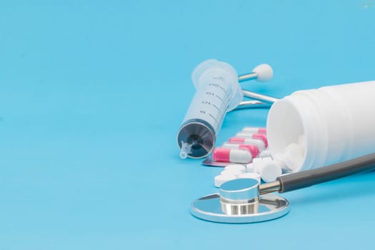 Tablet medical stethoscope and injection on a blue background