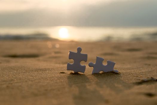 Jigsaw on the beach sand matching puzzle pieces together