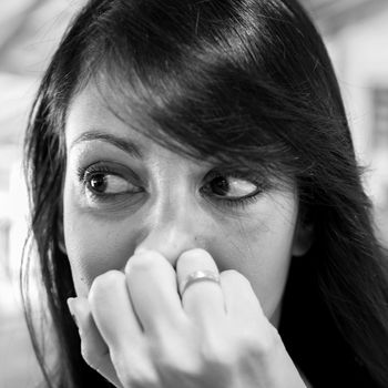 Pretty young woman with long black hair. Emotive portrait. Black and white (monochrome). Shallow depth of field.