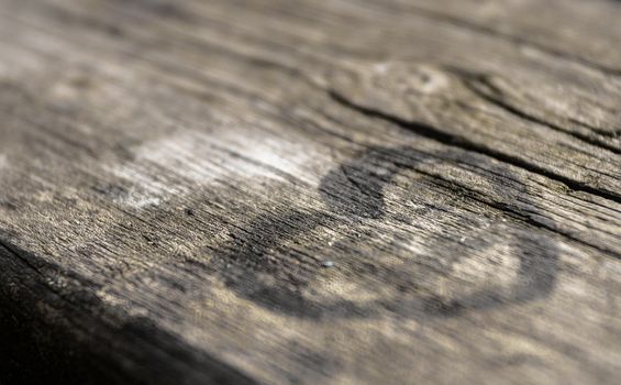 Black heart painted on a wooden table. Extreme close up. Defocused blurry background.