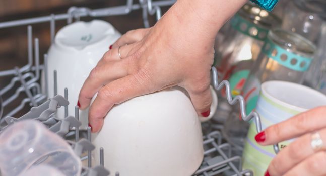 Close-up of a woman's hand filling a dishwasher machine