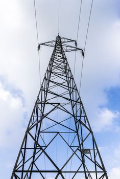 High voltage pylon against cloudy sky. Bottom view. Pattern of metal architecture.