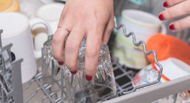 Close-up of a woman's hand filling a dishwasher machine