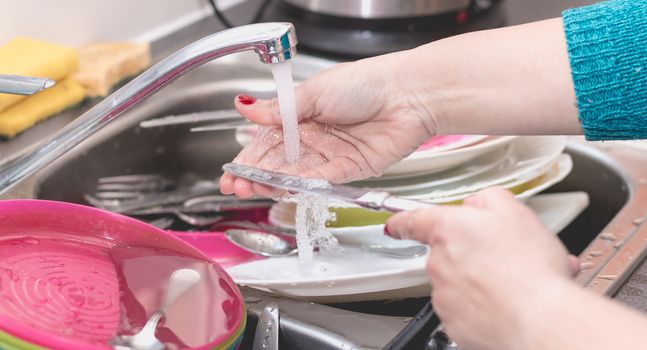 Close-up of a woman's hand filling a dishwasher machine