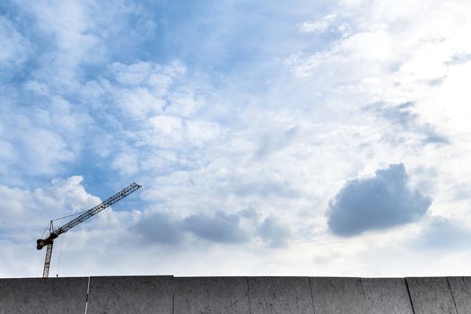 Crane used in construction site with blue sky and clouds