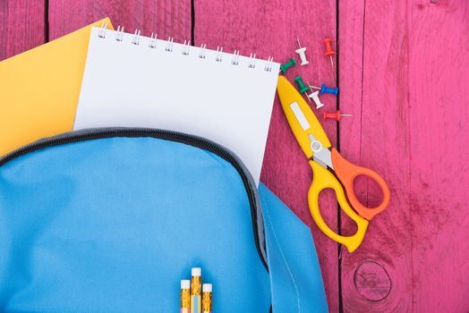 Top view flat lay of blue school bag backpack and accessories tools for children education on pink wood background, Back to school concept and have copy space for use