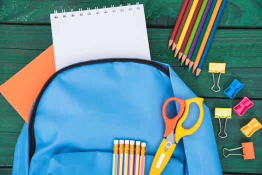 Top view flat lay of blue school bag backpack and accessories tools for children education on green wood background, Back to school concept and have copy space for use