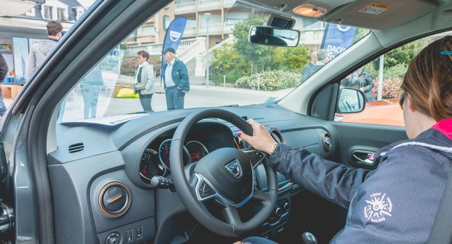 Sables d Olonnes, France - May 07, 2017 : Dacia Tour 2017 is a commercial operation organized by the car builder in order to present its cars throughout France - A woman watching a car