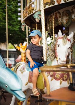 Little boy rides a traditional carousel white horse