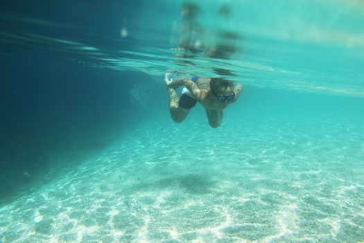 Child swimming underwater in blue transparent sea water in summer Croatia