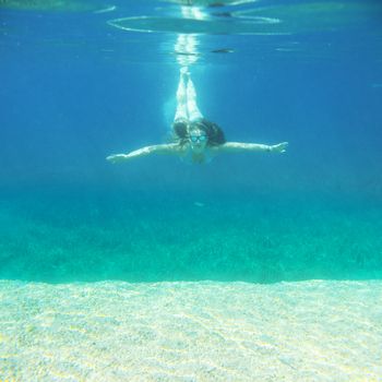 Woman swimming underwater in blue transparent sea water in summer Croatia