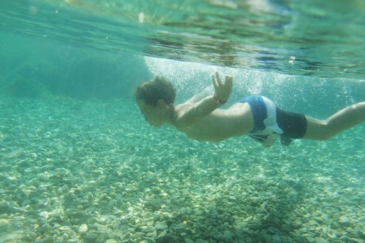 Child boy swimming underwater in mediterranean adriatic sea in Croatia