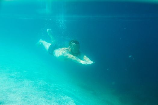 Mid adult bearded long hair man swimming underwater in mediterranean adriatic sea in Croatia