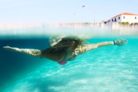 Woman swimming underwater in mediterranean adriatic sea in Croatia, old town of Sumartin