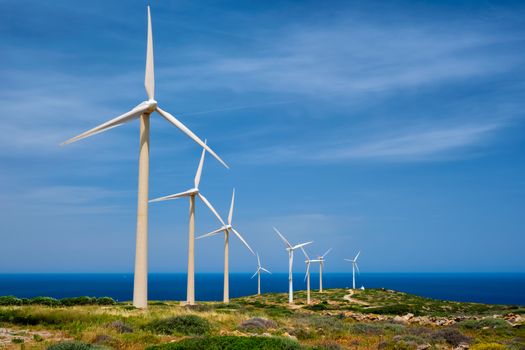 Green renewable alternative energy concept - wind generator turbines generating electricity. Wind farm on Crete island, Greece with road