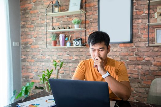 Asian man uses a notebook computer and works hard and meeting at home and he is stressed and Headache.