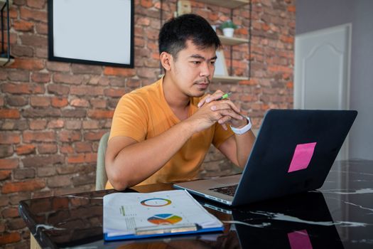 Asian man uses a notebook computer and works hard and meeting at home and he is stressed and Headache.