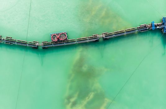 Aerial view of the long boom of a suction excavator in a quartz quarry for the excavation of white sand, made with drone