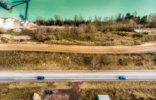 Aerial view of a road and a paved path at the edge of a sand quarry, made with drone