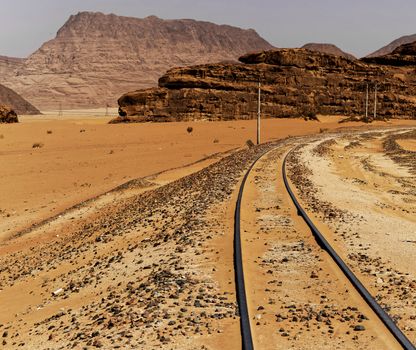 One-track railway with large rock formations in the background, in the desert of Wadi Rum, Jordan, middle east