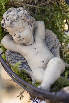 Tiny angel figurine in a moss bed in the garden