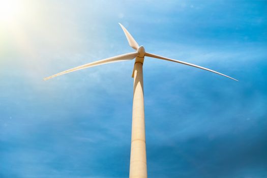 Green renewable alternative energy concept - wind generator turbine generating electricity in blue sky