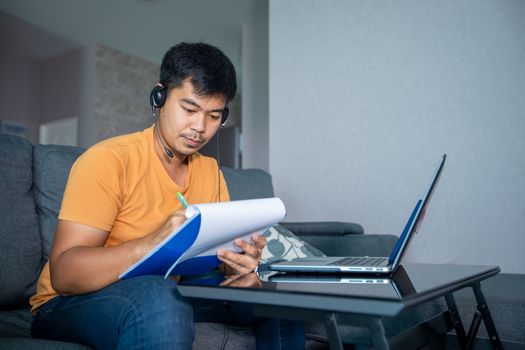 Asian businessmen is using notebook computers and wear headphones for online meetings and working from home.