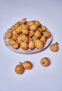 Medlars in a wooden plate and on the table, white, brown, natural, ecological, without retouching