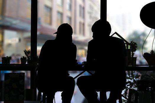 Shadow of couple sitting in coffee shop and looking out of windows.