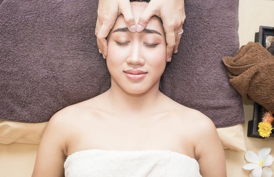 High angle view of an attractive young asian woman receiving facial massage at spa center