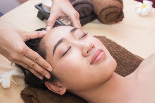 Beautiful young asian girl having face massage in spa salon