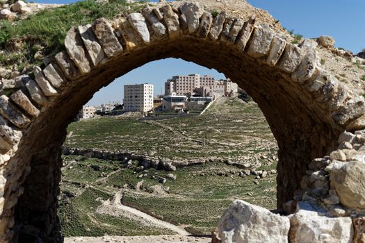 Skyscraper in the suburb of Karak in Jordan, photographed by a wall arch at the wall of the crusader castle, middle east