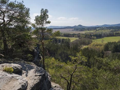 Spring landscape in Lusatian Mountains view from sandstone rocks, green hills, fresh deciduous and spruce tree forest. Blue sky background, horizontal, copy space.