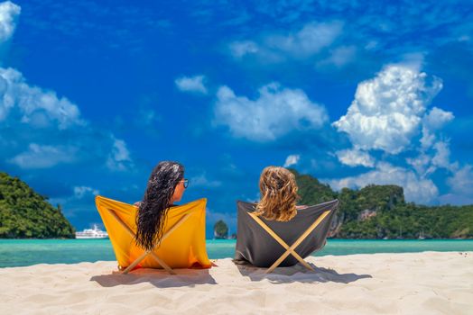 Two women sitting on sunbeds at the beach