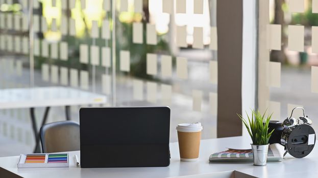 Back view cropped shot of Laptop, coffee cup, alarm clock, potted plant, color, color guide on the working desk,