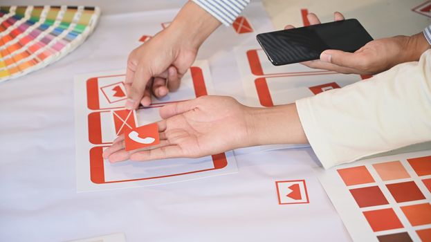 Top view of Ux Ui creative team while brainstorming/deciding on the icon at the work desk.