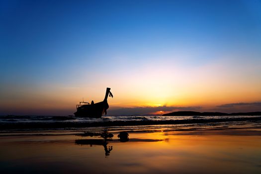 Traditional long-tail boat on the beach at sunset in Thailand