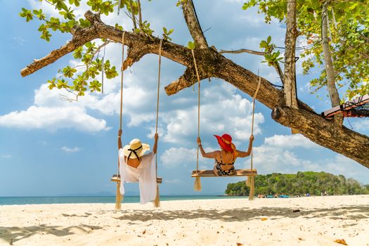 Two beautiful Women on a swing at the beach in Thailand