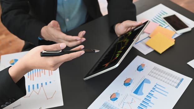 Cropped shot of businessmen discussing/analyzing about financial and business growing by using tablet with candle chart on screen.