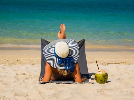 Woman with straw hat enjoying her holidays on a transat at the tropical beach in Thailand