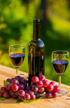 wine bottle and grapes on wooden table, outdoor