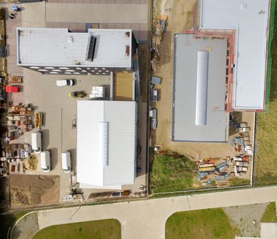 Abstract vertical aerial view of two newly built industrial halls in an industrial area, made with drone