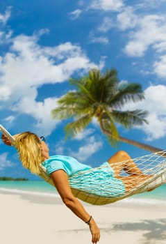 Woman sitting in hammock on the beach. Travel and vacation concept.