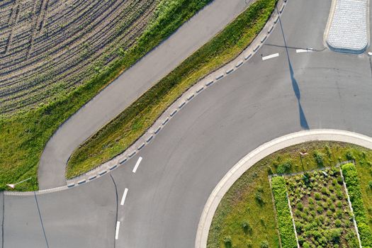 Abstract vertical aerial view of a cut roundabout next to an area of arable land, made with drone
