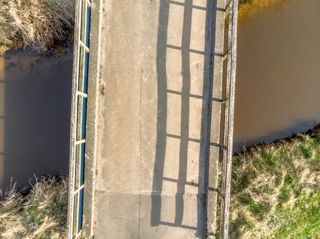 Aerial view from a low height of 10 meters from a small bridge over a dark stream , made with drone