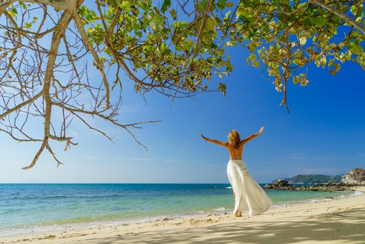 Woman in white walking on thetropical  beach in the summertime