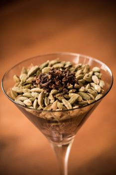 Green and black cardamom and clove spices in a cocktail glass